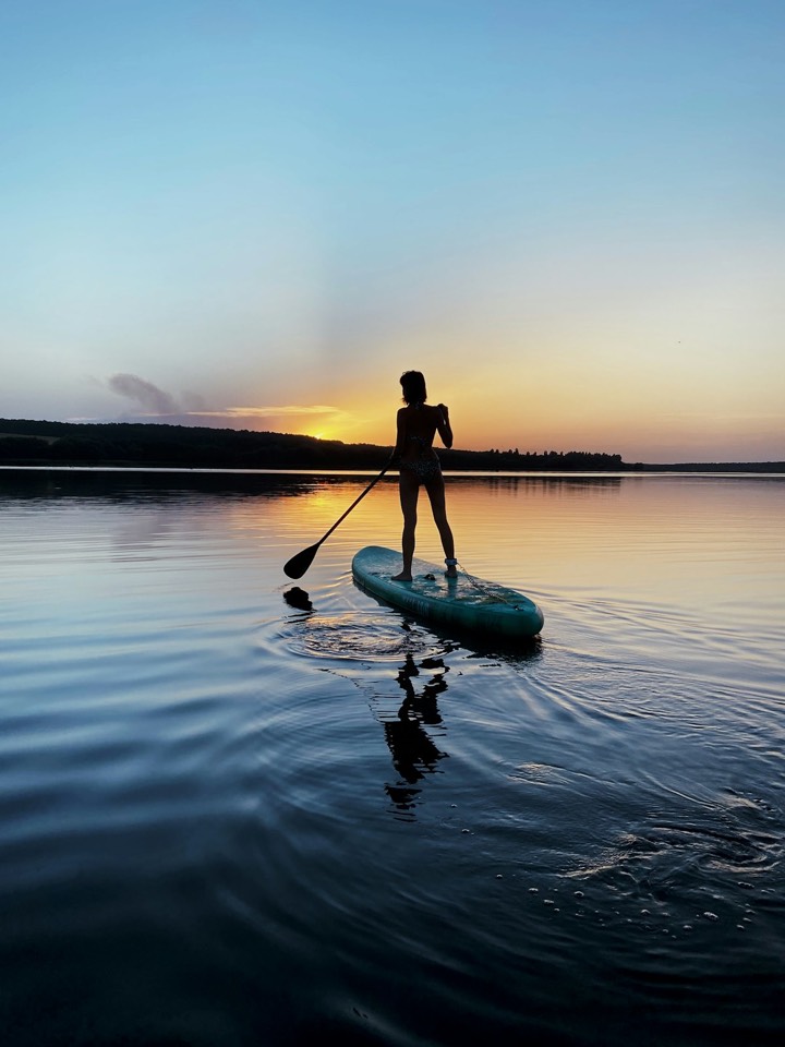 A paddleboarder on the water at sunset