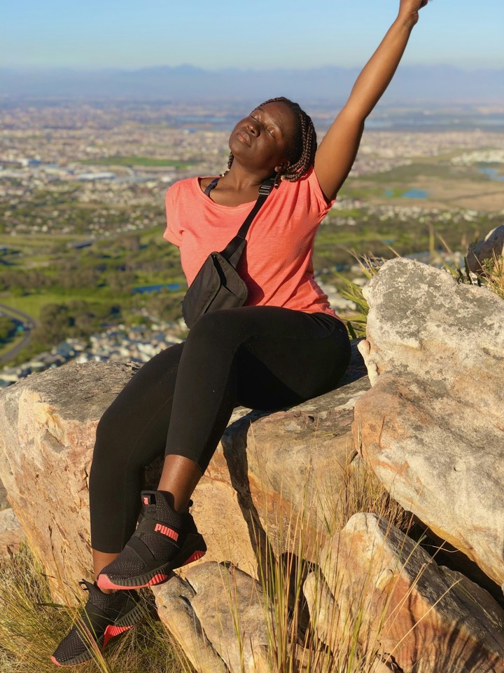 A woman resting on a rock on a mountain hike