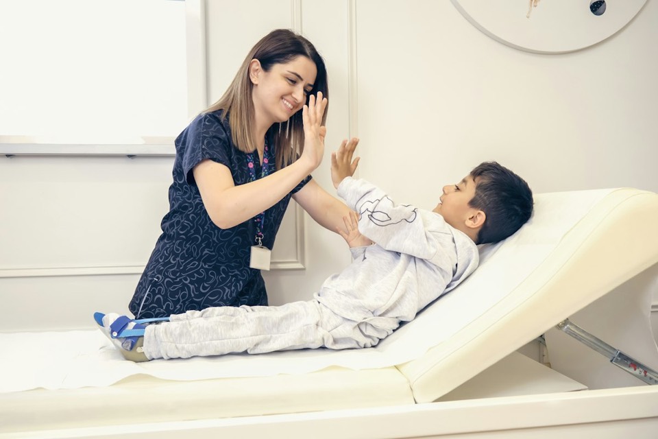 A physical therapist high-fiving a young patient